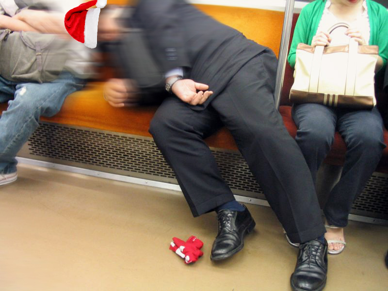 A pixelated, black and white image of a Japanese salary man asleep on the subway